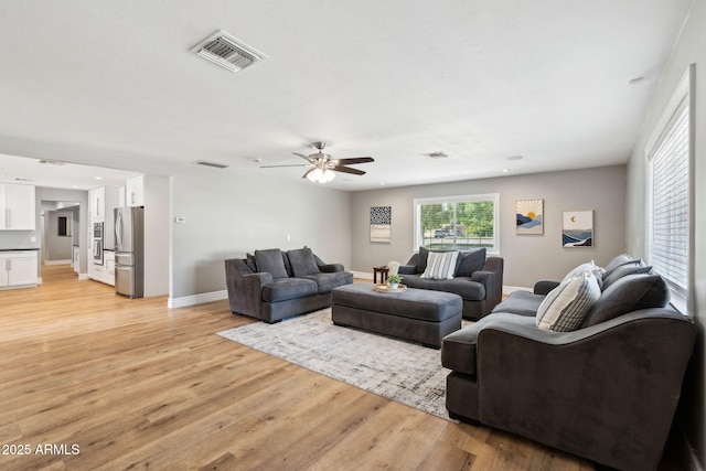 living area with visible vents, a ceiling fan, and light wood-type flooring
