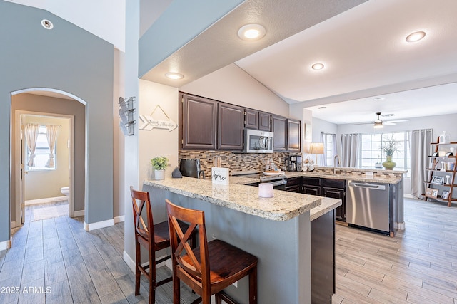 8510 W Joan De Arc Ave, Peoria, AZ 85381 - kitchen with light wood-type flooring, stainless steel appliances, a peninsula, and decorative backsplash