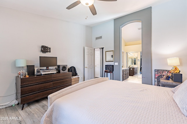 8510 W Joan De Arc Ave, Peoria, AZ 85381 - bedroom featuring connected bathroom, arched walkways, light wood-style flooring, a high ceiling, and visible vents