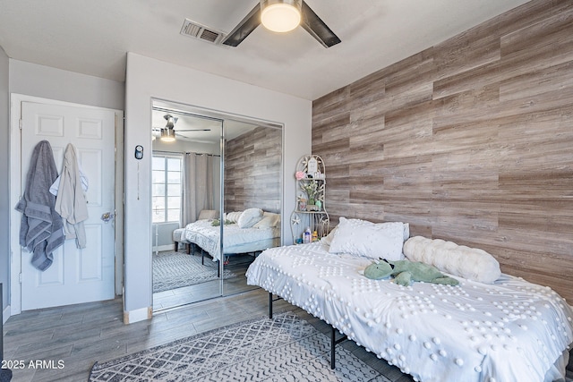 8510 W Joan De Arc Ave, Peoria, AZ 85381 - bedroom featuring wood walls, wood finished floors, visible vents, an accent wall, and a closet