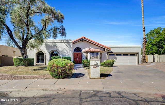 mediterranean / spanish-style home with driveway, a tile roof, an attached garage, and stucco siding