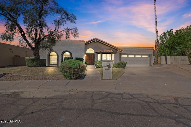 view of front of house with concrete driveway, a tile roof, an attached garage, and stucco siding