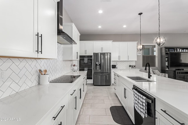 kitchen with white cabinetry, decorative light fixtures, black appliances, sink, and wall chimney exhaust hood