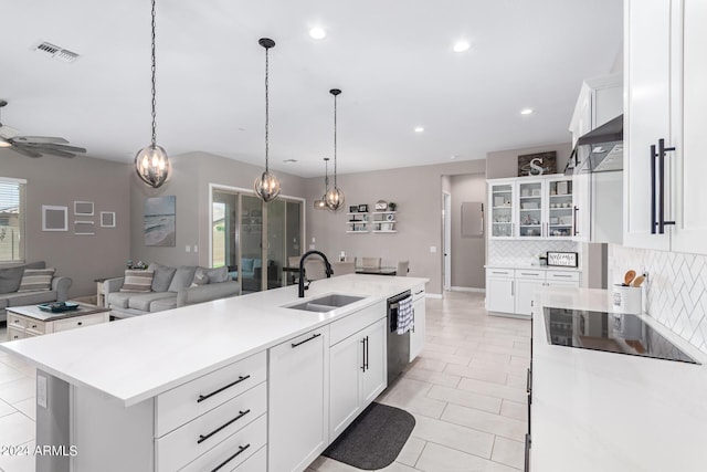 kitchen featuring sink, decorative light fixtures, black appliances, white cabinets, and an island with sink