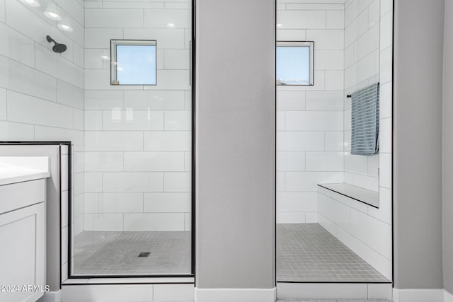 bathroom featuring vanity, a tile shower, and a wealth of natural light