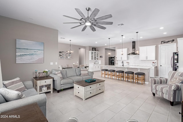 tiled living room featuring ceiling fan with notable chandelier and sink