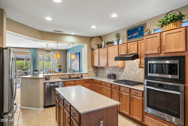 kitchen featuring visible vents, a sink, under cabinet range hood, backsplash, and stainless steel appliances