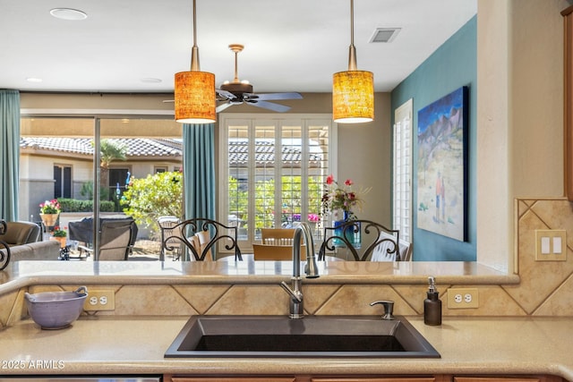 kitchen featuring a wealth of natural light, visible vents, decorative light fixtures, and a sink