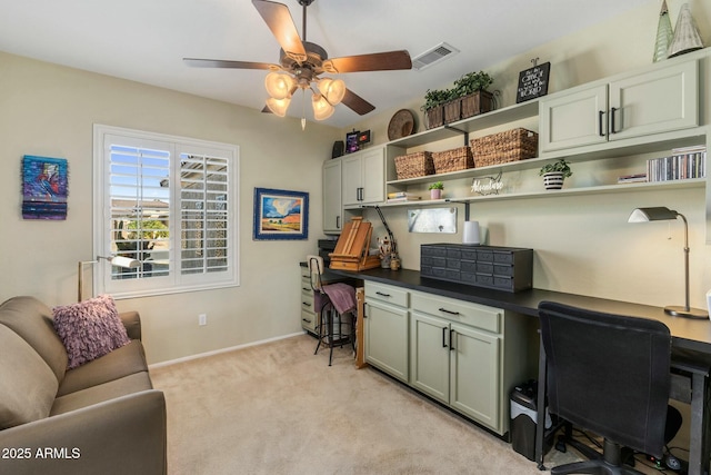 office space with a ceiling fan, baseboards, visible vents, built in desk, and light colored carpet