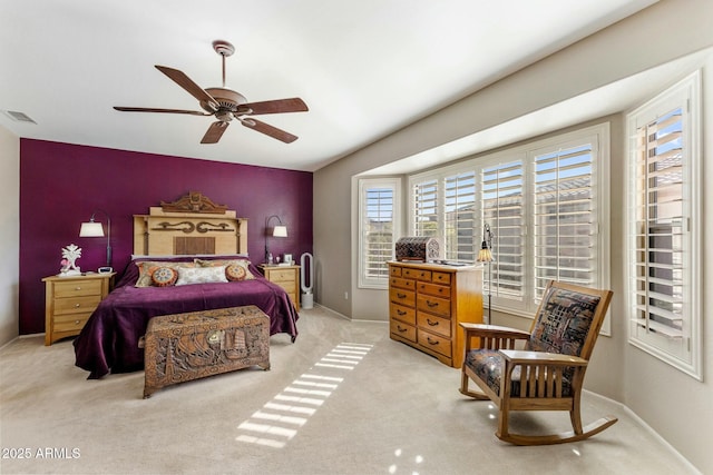 bedroom featuring baseboards, visible vents, ceiling fan, light carpet, and an accent wall