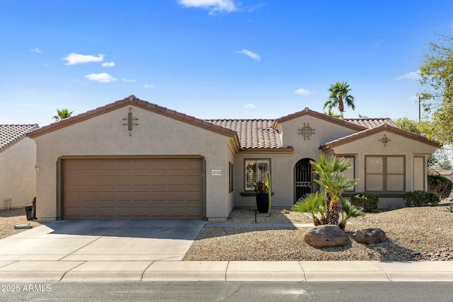 mediterranean / spanish-style house featuring stucco siding, a garage, concrete driveway, and a tiled roof