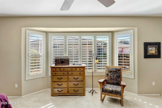 sitting room featuring light colored carpet, baseboards, and ceiling fan