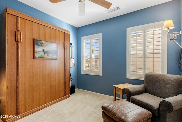 living area featuring visible vents, baseboards, carpet, and ceiling fan