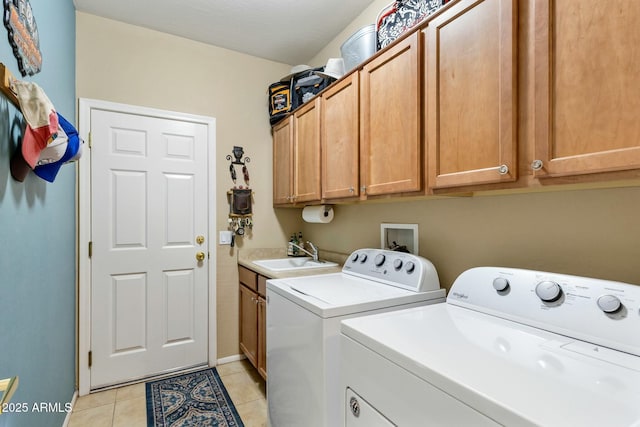 laundry room featuring a sink, cabinet space, light tile patterned floors, baseboards, and washing machine and clothes dryer