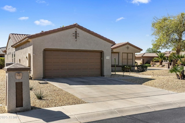 mediterranean / spanish home featuring concrete driveway, an attached garage, a tile roof, and stucco siding