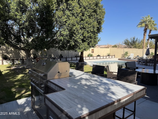 exterior space with a fenced in pool, a patio, and an outdoor kitchen