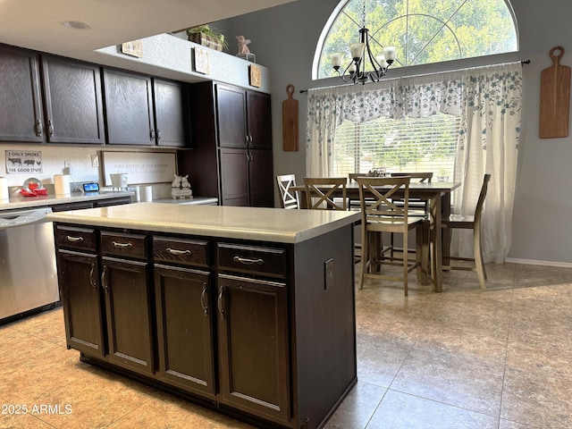 kitchen with light tile patterned floors, dishwasher, dark brown cabinets, a center island, and a notable chandelier