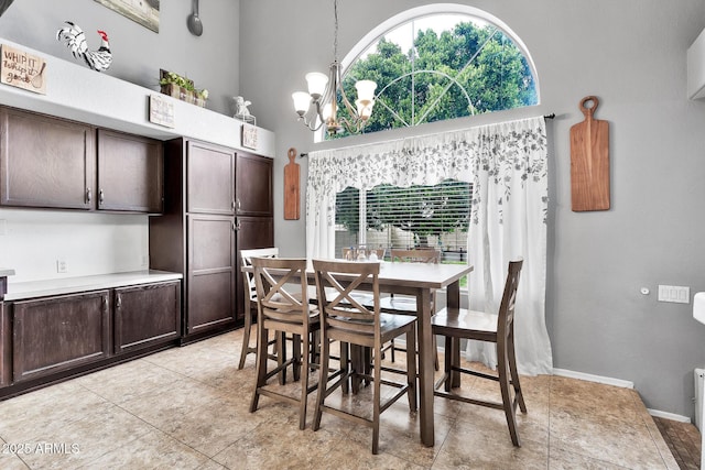 dining space with a notable chandelier, a towering ceiling, and light tile patterned floors