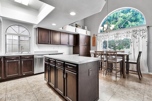 kitchen with dark brown cabinetry, sink, stainless steel dishwasher, a kitchen island, and pendant lighting