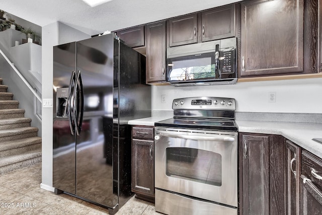 kitchen with dark brown cabinetry, electric range, light tile patterned flooring, and black fridge