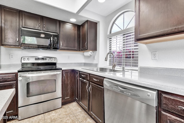 kitchen featuring stainless steel appliances, light tile patterned flooring, dark brown cabinets, and sink