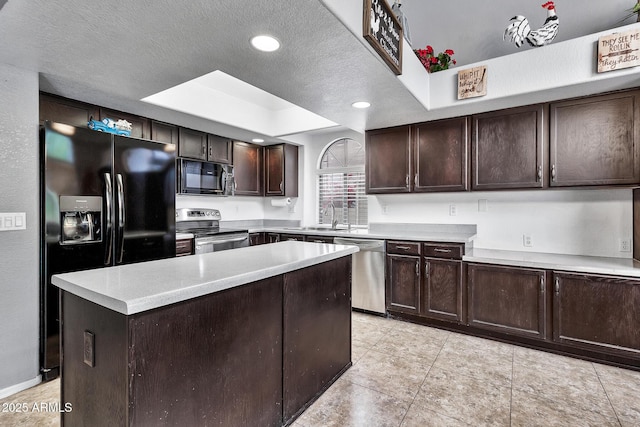 kitchen with sink, a tray ceiling, black appliances, a textured ceiling, and a kitchen island