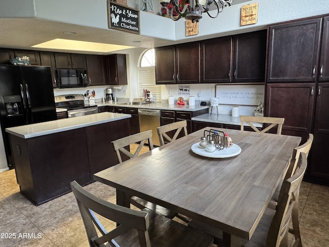 kitchen featuring light tile patterned flooring, a kitchen island, a chandelier, dark brown cabinetry, and black appliances