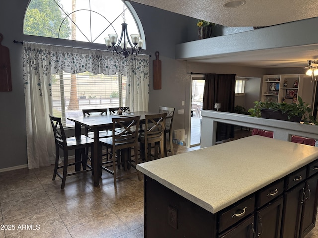 kitchen with light tile patterned flooring, a healthy amount of sunlight, ceiling fan with notable chandelier, and a kitchen island