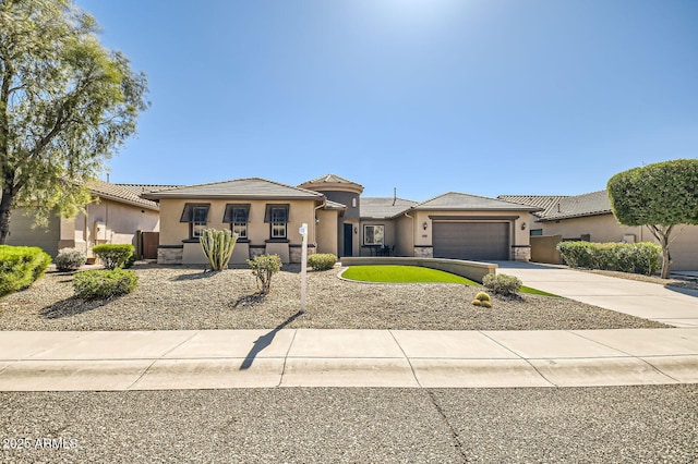 prairie-style house featuring stucco siding, stone siding, concrete driveway, an attached garage, and a tiled roof