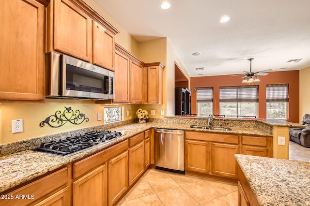 kitchen featuring light stone counters, a ceiling fan, a peninsula, a sink, and stainless steel appliances