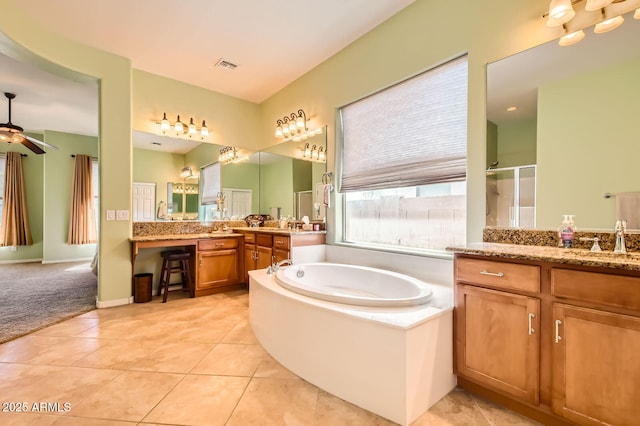 bathroom with visible vents, a garden tub, two vanities, a sink, and tile patterned flooring