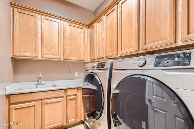 clothes washing area featuring a sink, cabinet space, and washer and dryer