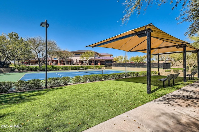 view of property's community featuring a tennis court, a yard, and fence