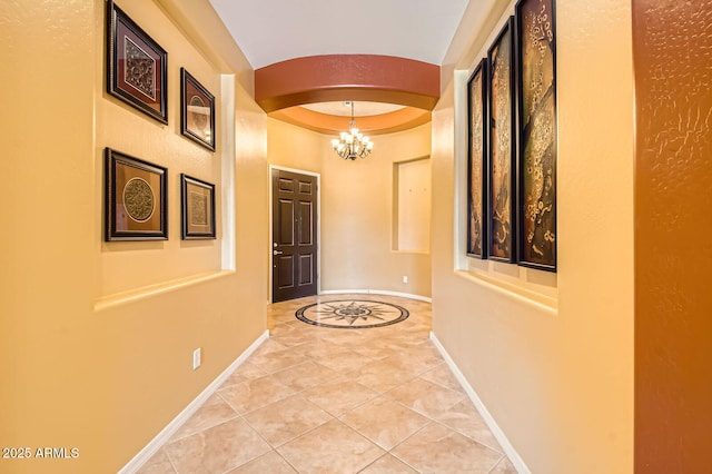 entryway featuring arched walkways, an inviting chandelier, baseboards, and light tile patterned flooring