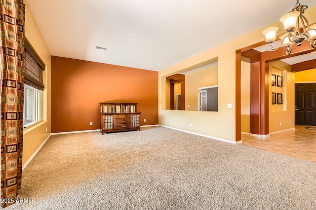 tiled empty room with a notable chandelier, carpet flooring, baseboards, and visible vents