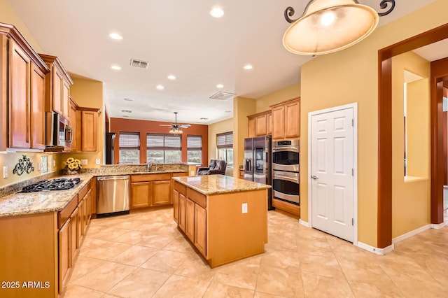 kitchen featuring light stone countertops, visible vents, a kitchen island, a sink, and stainless steel appliances