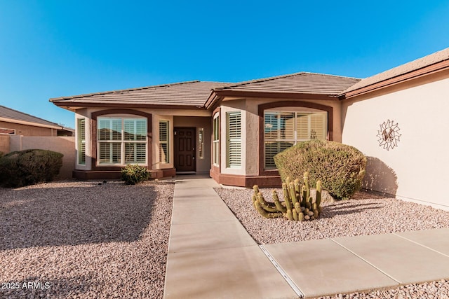 doorway to property featuring a tiled roof and stucco siding