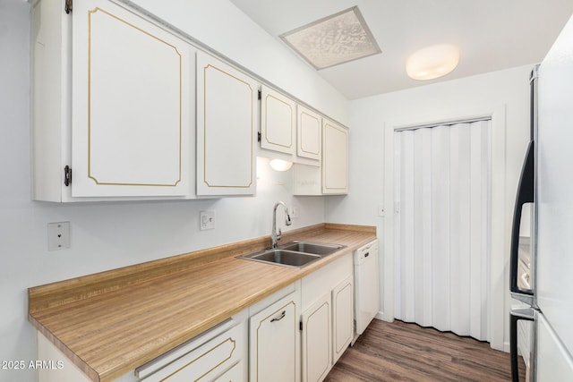 kitchen featuring light countertops, white appliances, a sink, white cabinets, and wood finished floors