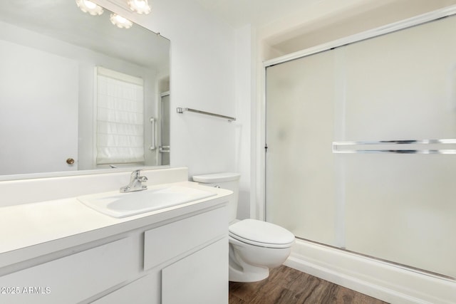 bathroom featuring toilet, vanity, an enclosed shower, and wood finished floors
