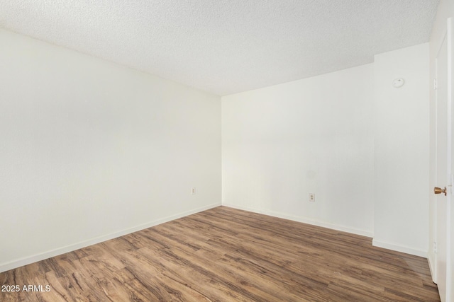 unfurnished room featuring baseboards, wood finished floors, and a textured ceiling