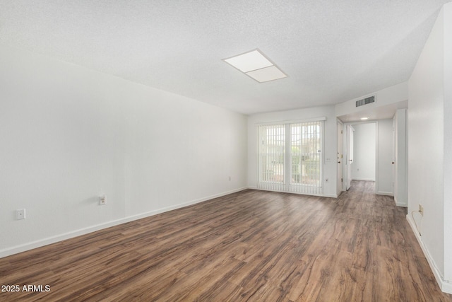 empty room featuring baseboards, a textured ceiling, visible vents, and wood finished floors