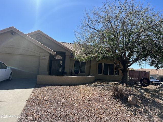 ranch-style house with a garage, fence, a tile roof, concrete driveway, and stucco siding