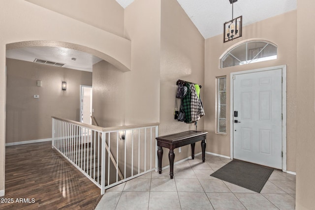 tiled entrance foyer featuring arched walkways, visible vents, and baseboards