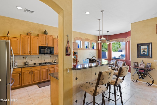 kitchen featuring a kitchen breakfast bar, light tile patterned floors, hanging light fixtures, and appliances with stainless steel finishes