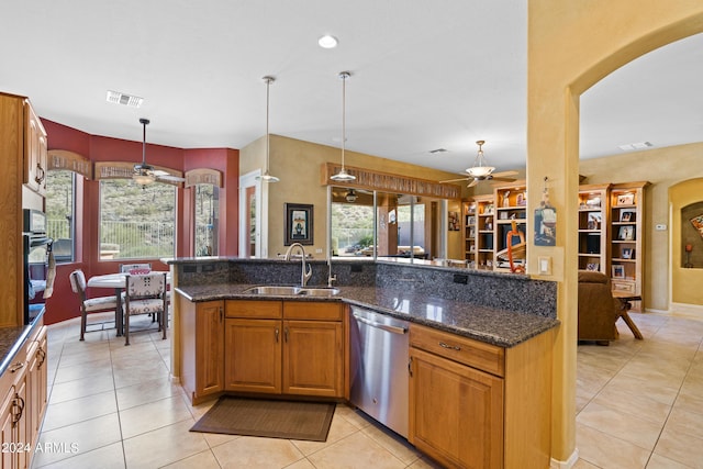 kitchen featuring dishwasher, sink, hanging light fixtures, dark stone counters, and light tile patterned floors