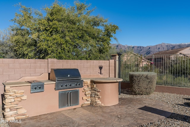 view of patio / terrace featuring a mountain view, an outdoor kitchen, and a grill