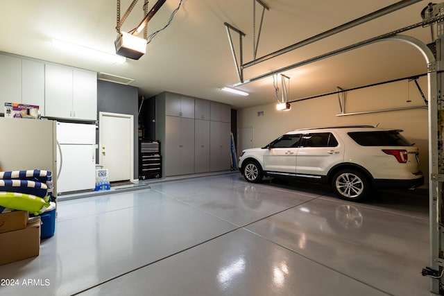 garage featuring white refrigerator and a garage door opener