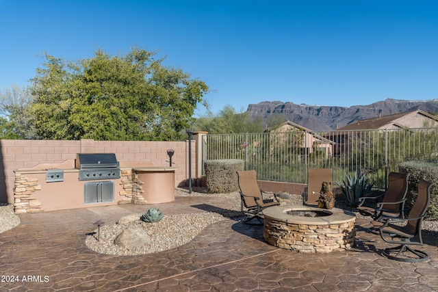 view of patio / terrace with area for grilling, a mountain view, grilling area, and an outdoor fire pit