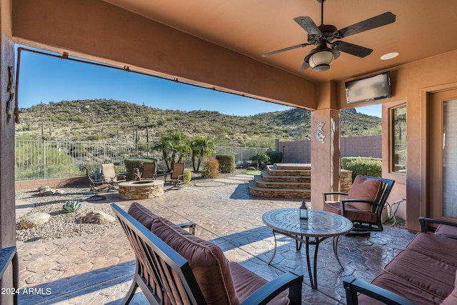 view of patio / terrace with ceiling fan and an outdoor living space with a fire pit