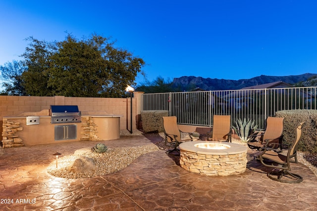 view of patio / terrace with a grill, a mountain view, exterior kitchen, and an outdoor fire pit